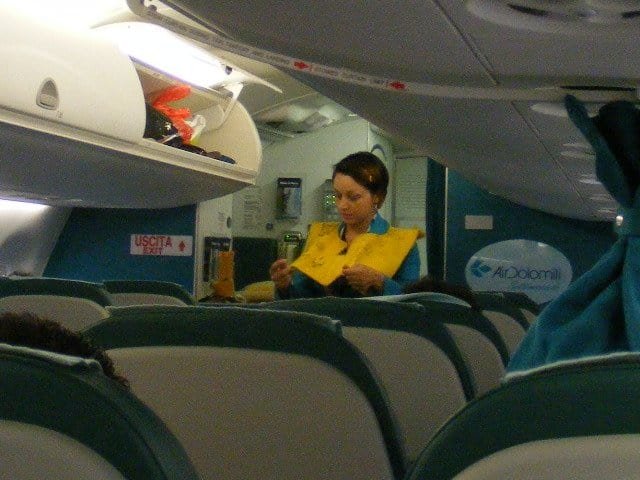 Comissária de bordo da Air Dolomiti em uniforme dentro da aeronave