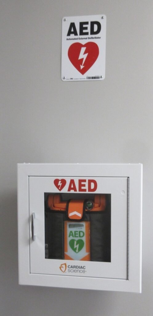 Desfibrilador Externo Automático (DEA) instalado em compartimento de parede, equipamento semelhante ao levado a bordo de aviões