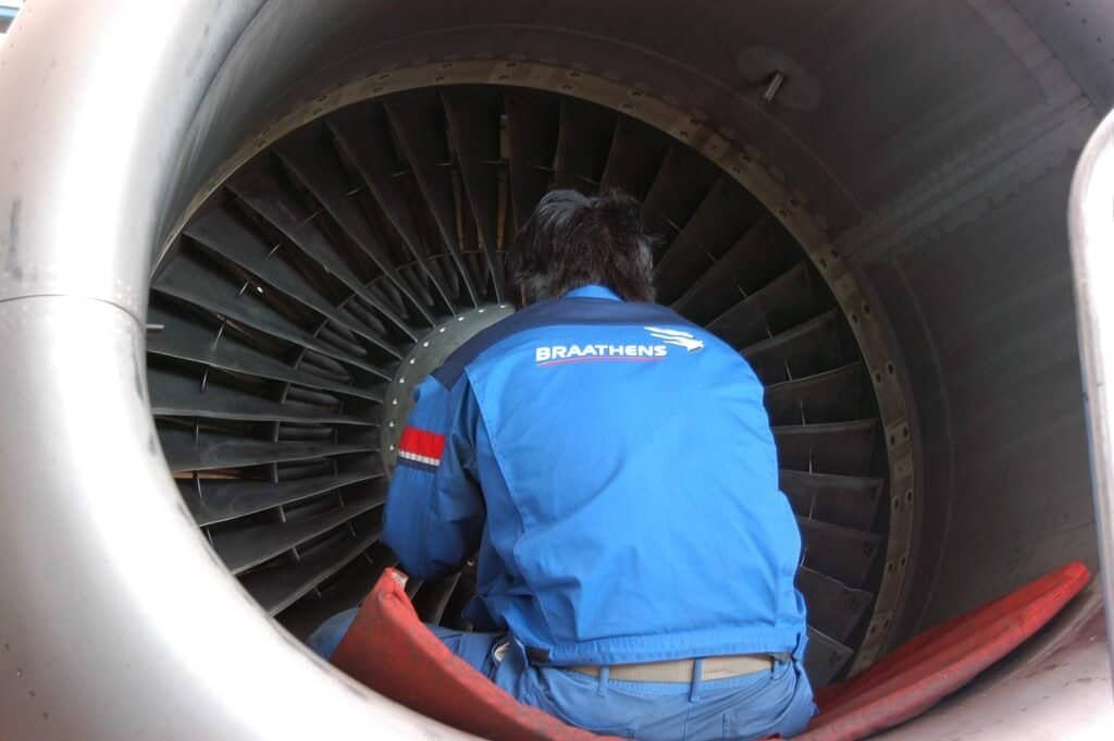 Técnico de manutenção trabalhando no motor turbofan de um avião, área onde fica o sistema FADEC de controle eletrônico